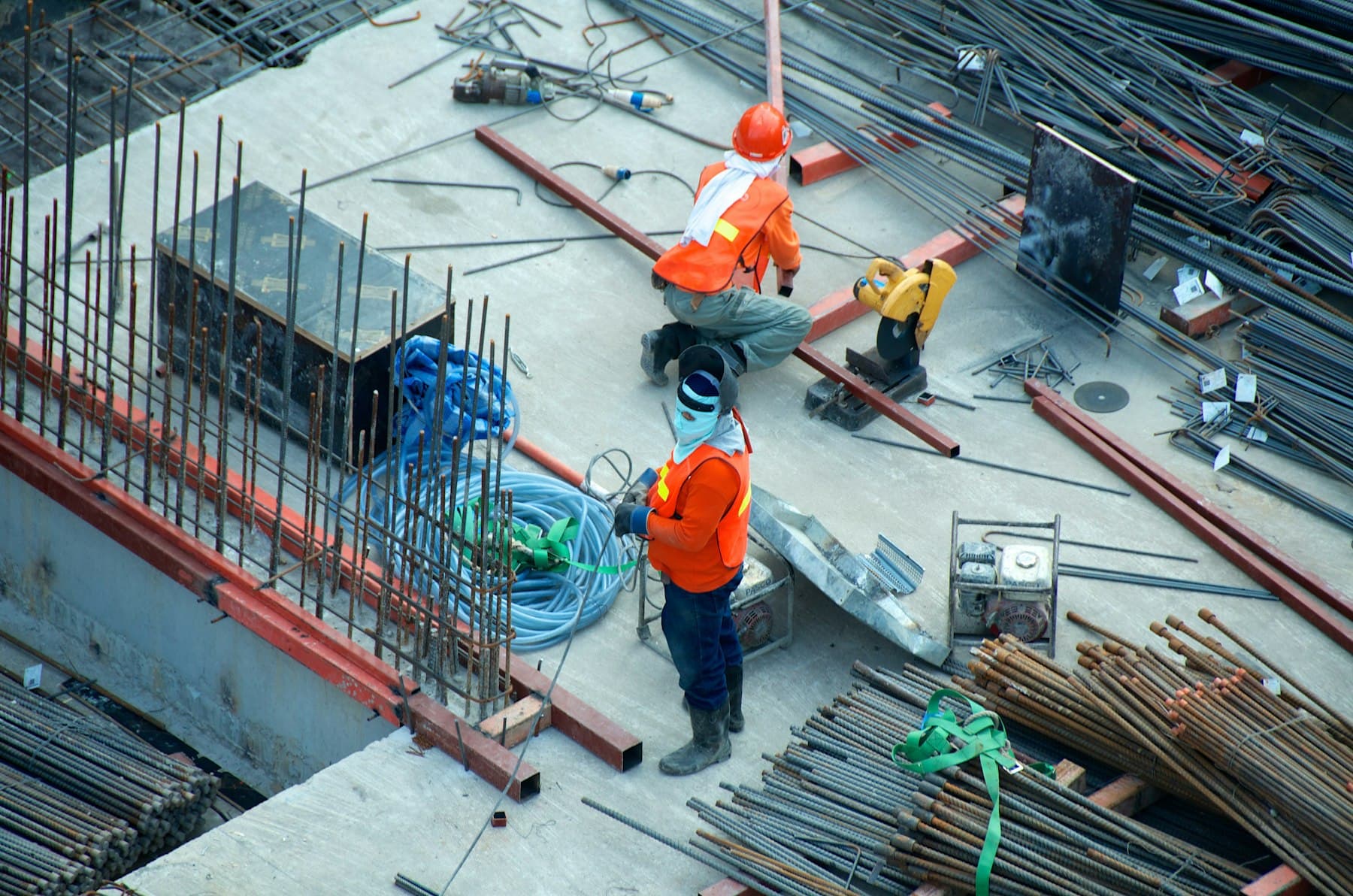 Construction workers in orange vests on a building site seen from above